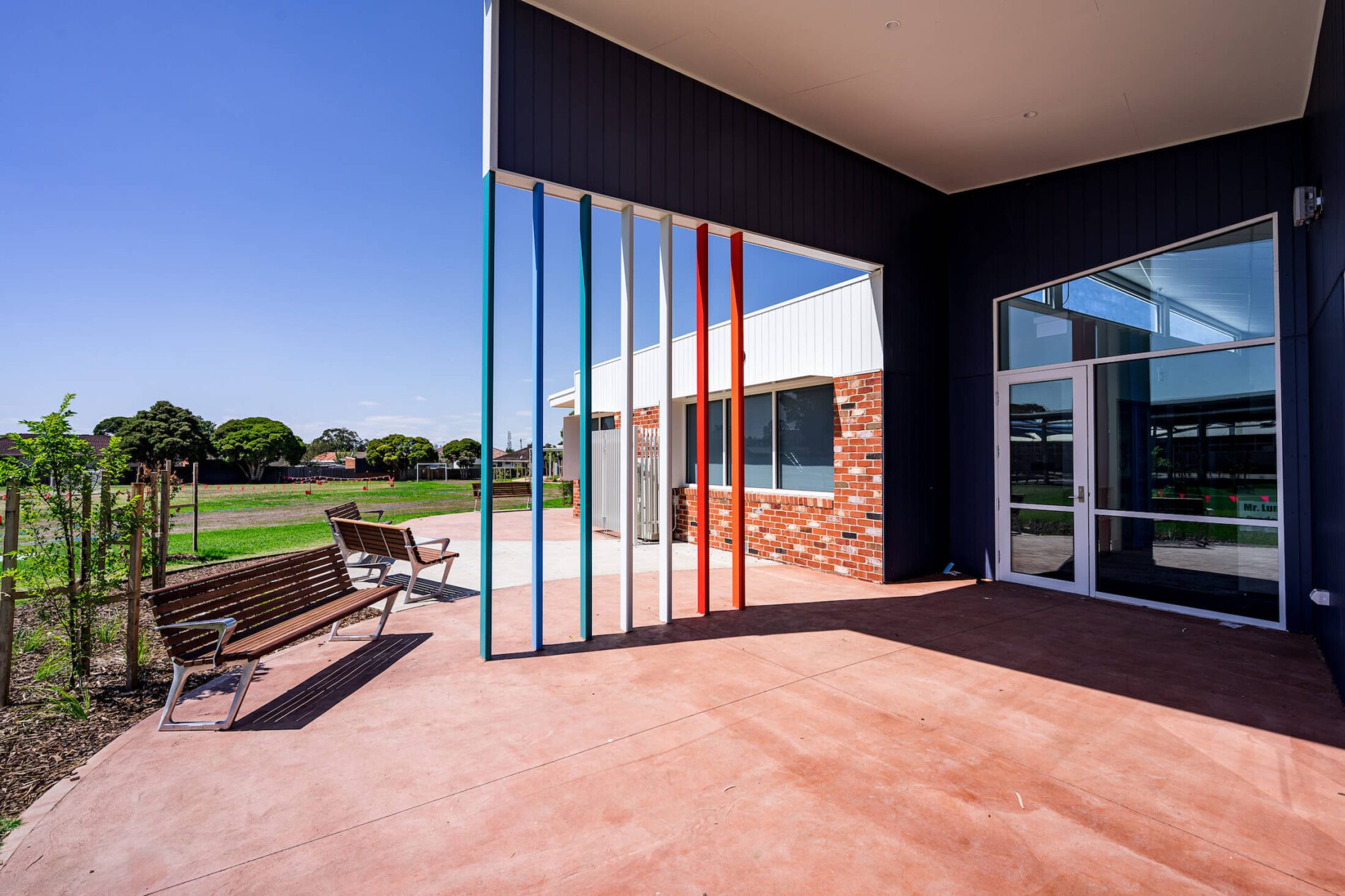 Colourful feature and school entry canopy with seating and oval beyond