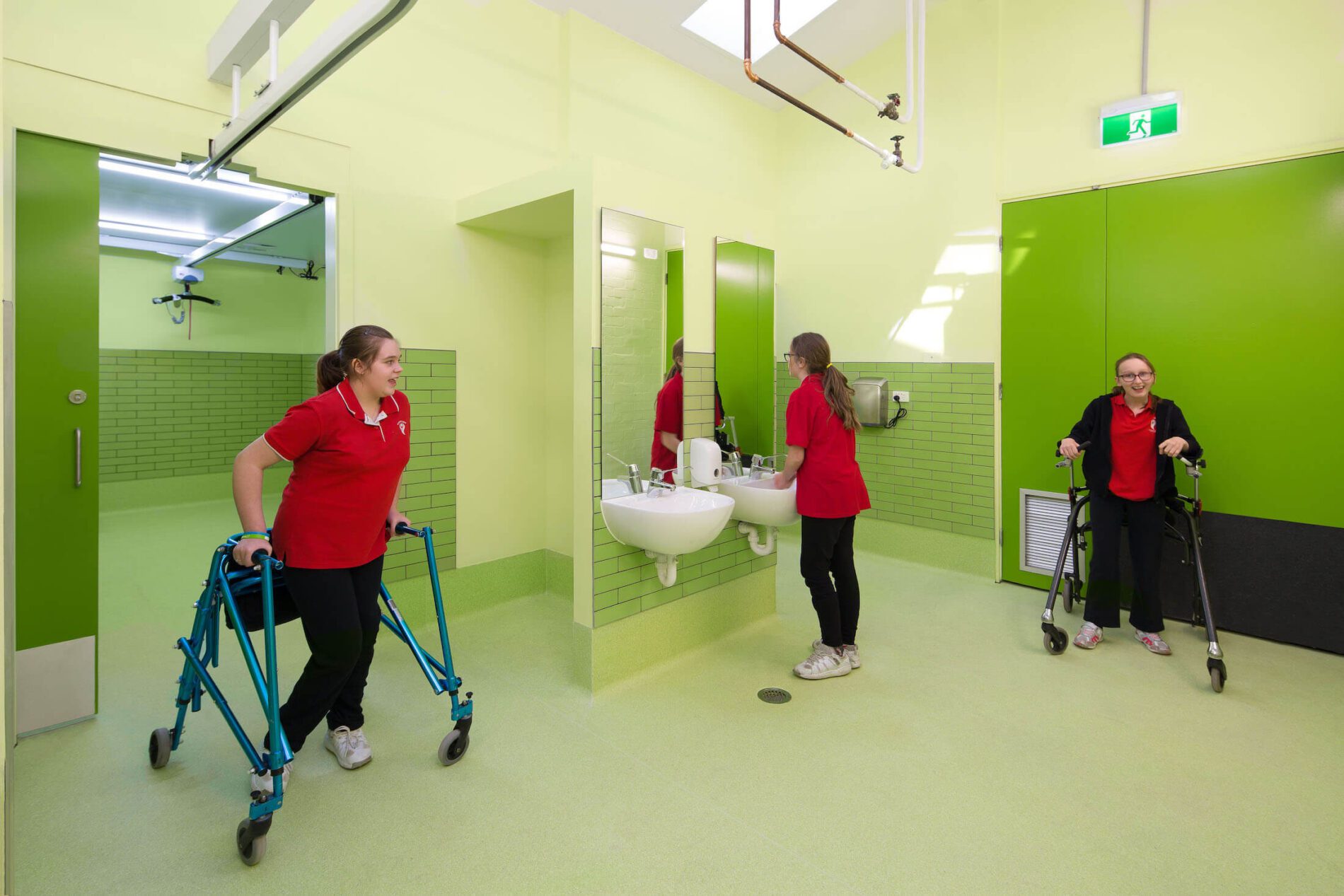 Three female students - two using walkers - use green toilet block and change rooms