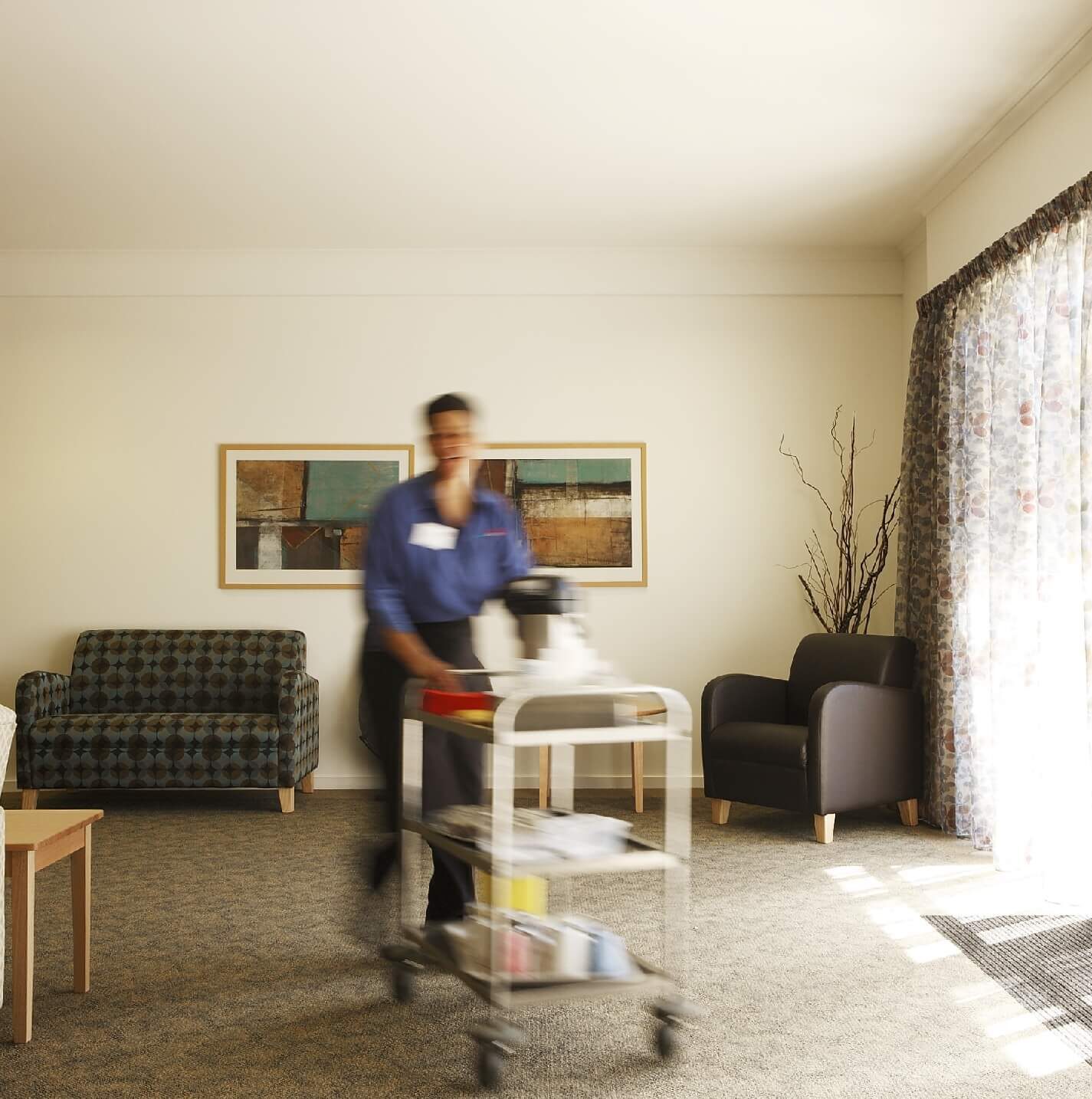 Carer pushes a trolly through an aged care living room