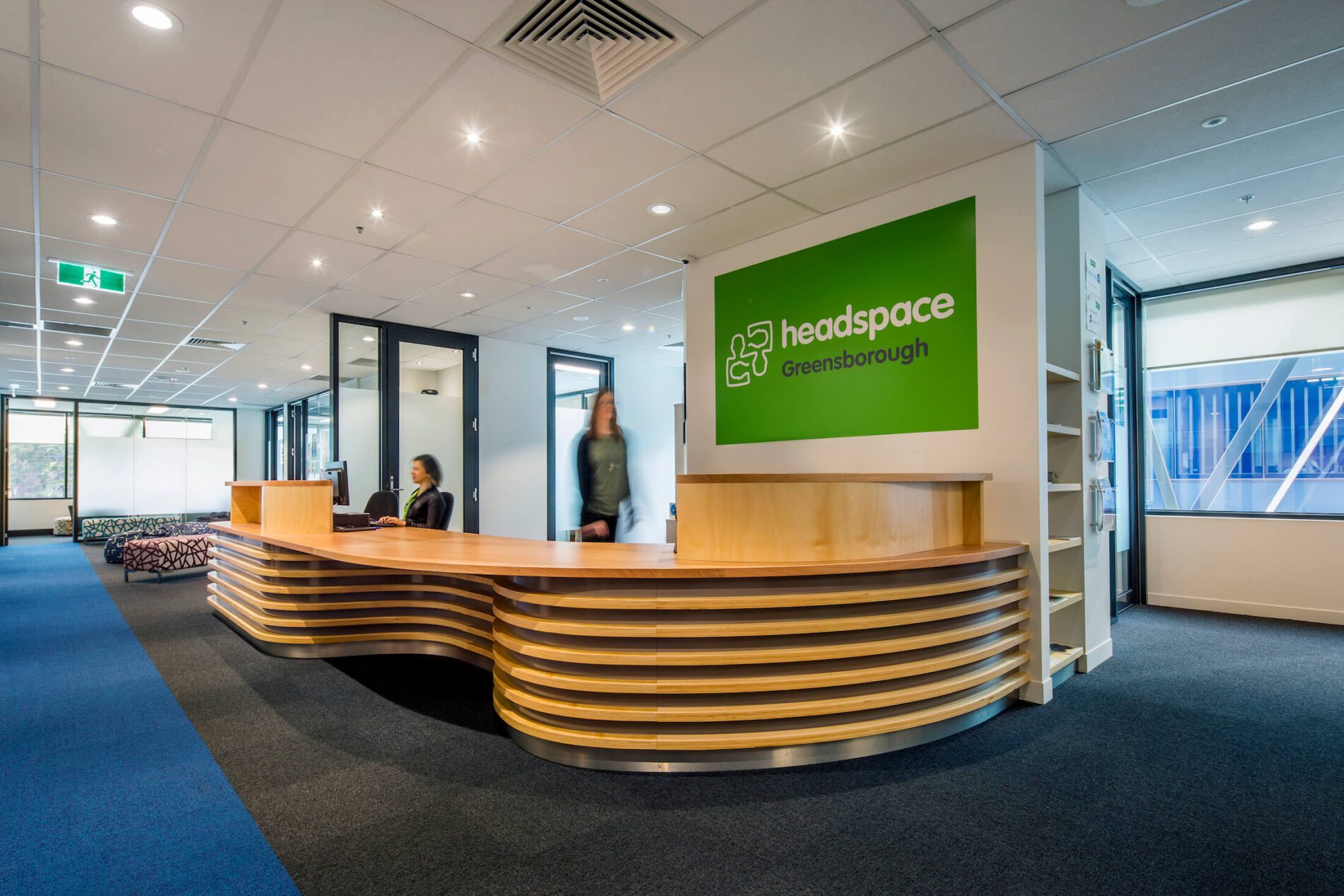 Reception desk with ribbed timber detail, green sign behind desk showing "headspace Greensborough"