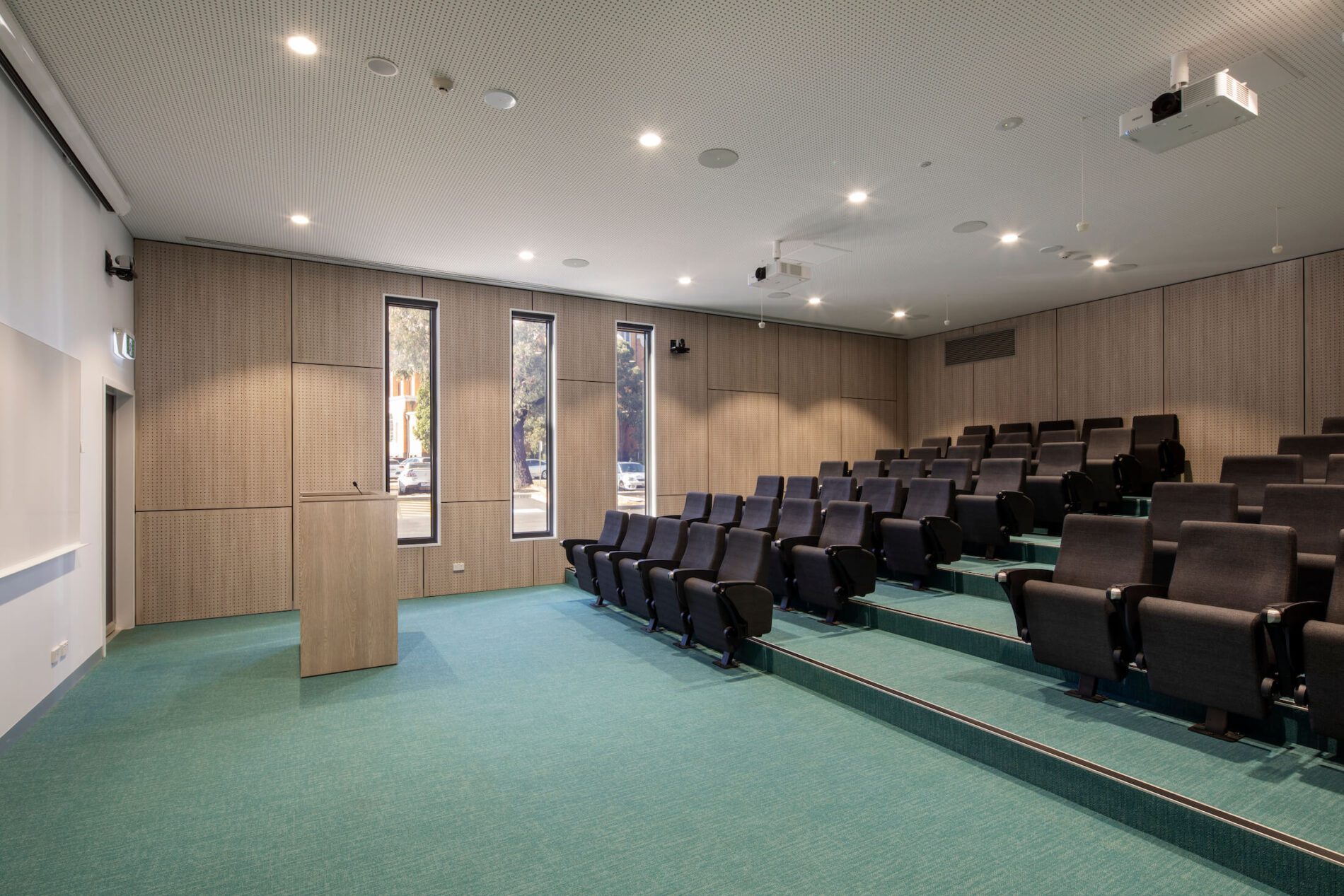 Tiered seating lecture theatre with timber veneer laminate podium and perforated veneer wall panels