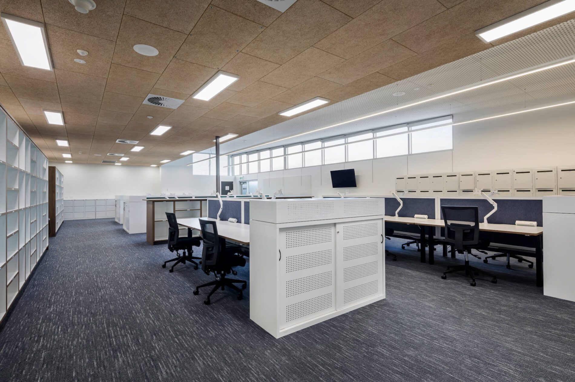 Office space with desks, acoustic ceiling and perforated cabinetry, pigeonholes