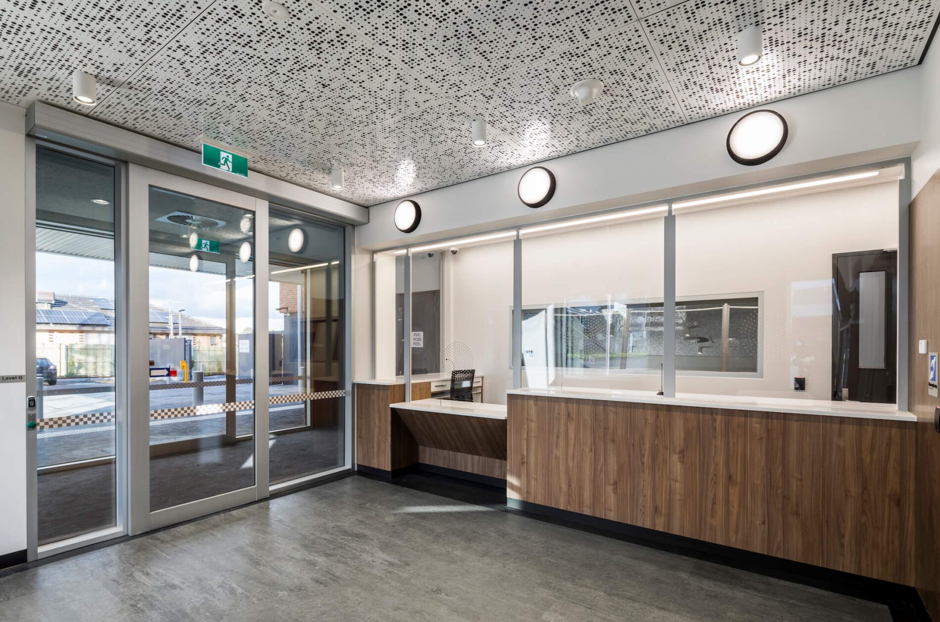 Frontline police reception area with perforated ceiling detail, timber laminate and circular lights