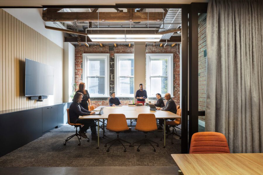 Six staff members meet in warehouse style office boardroom