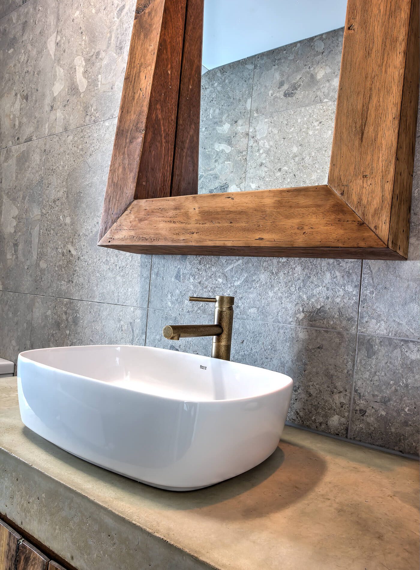 Porcelain basin with chrome tapware, stone bench and timber framed mirror