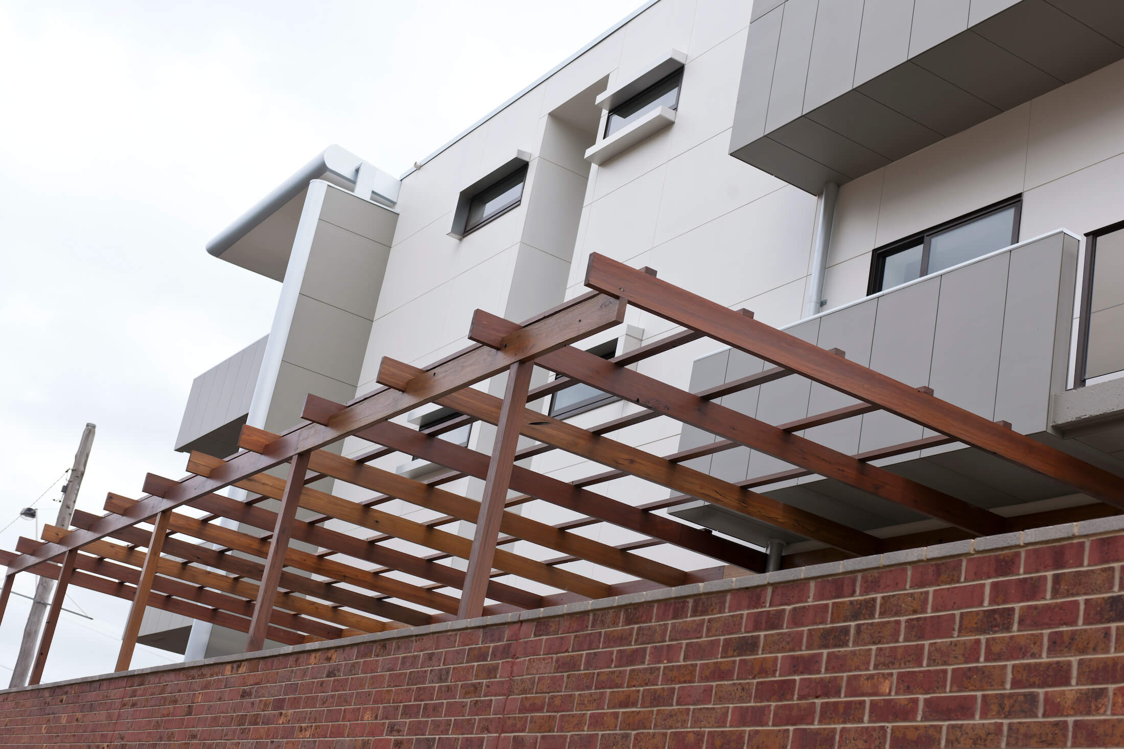 Timber structure over outdoor area, contemporary clad apartment building above