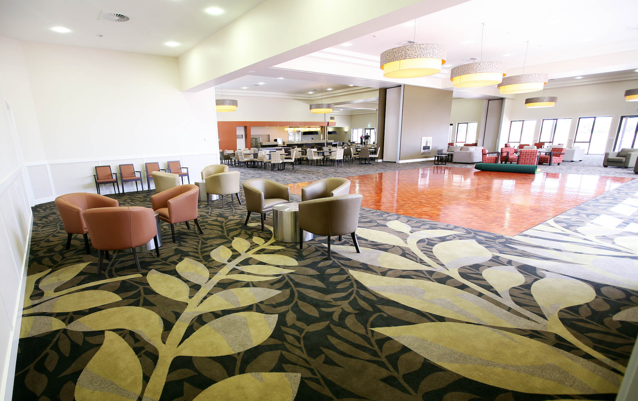 Retirement village carpeted area with lounges and parquet dancefloor, dining beyond
