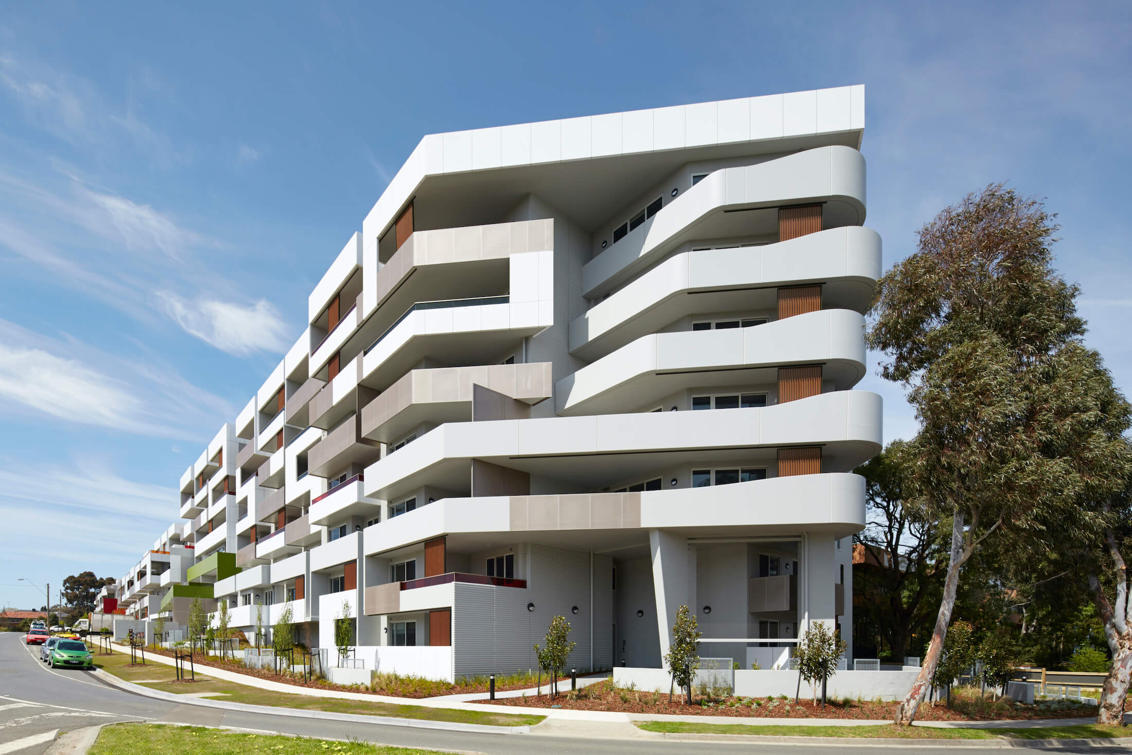 A multi-level apartment building with native landscaping and a curved end to the facade