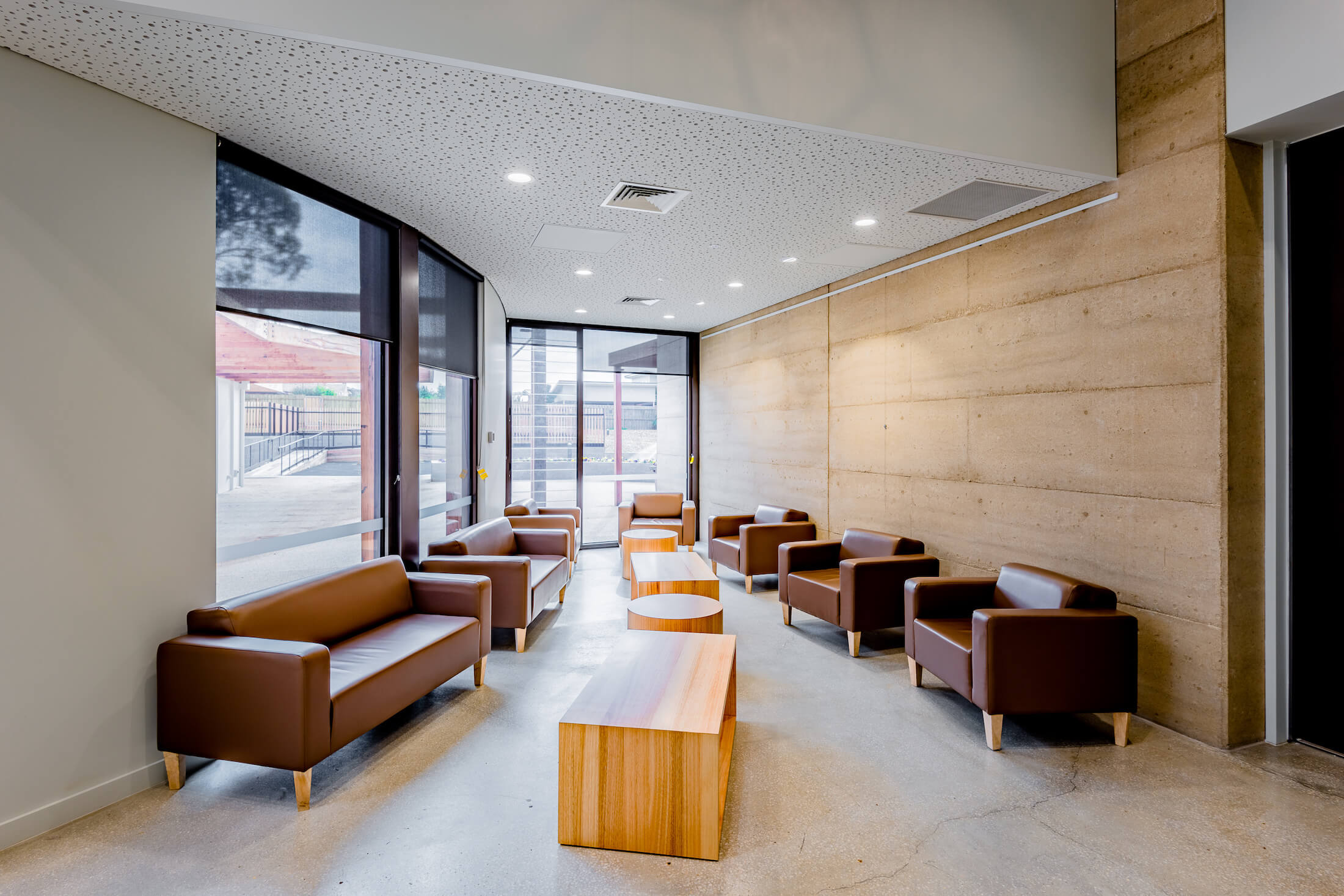 Leather look lounges and timber coffee tables in seating nook overlooking courtyard