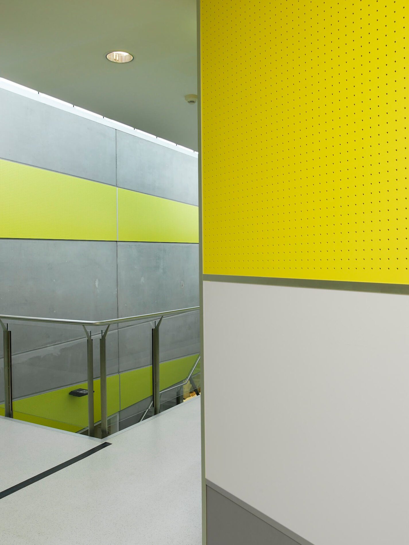 Perforated yellow cladding detail on internal skin of circulation and stairwell within concrete police complex