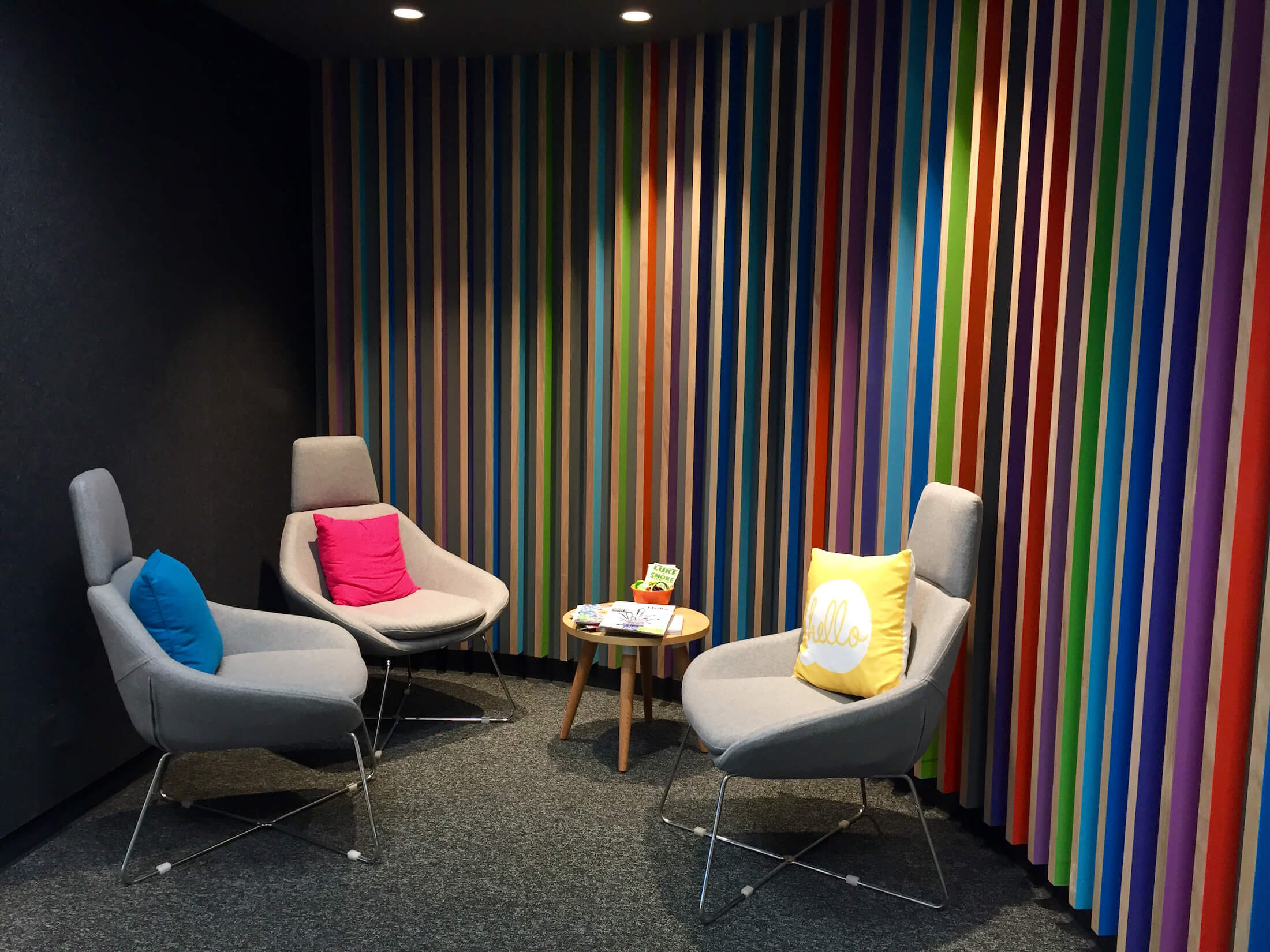 Ribbed rainbow panelling wall detail behind armchairs with colourful cushions
