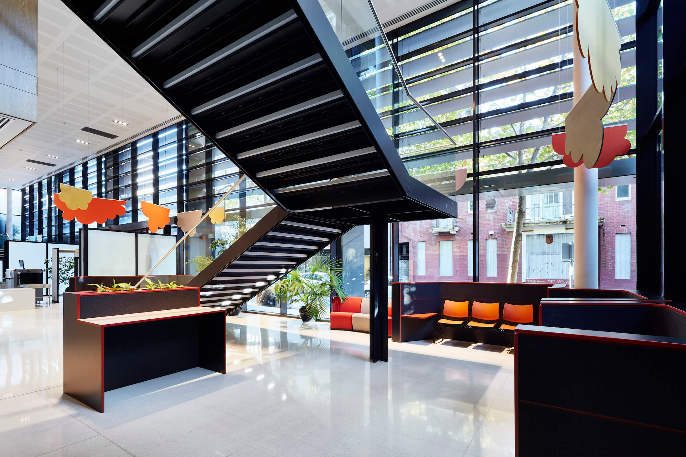 Foyer area with coloured seating and standing desks, external shading on building and colourful cloud acoustic panels
