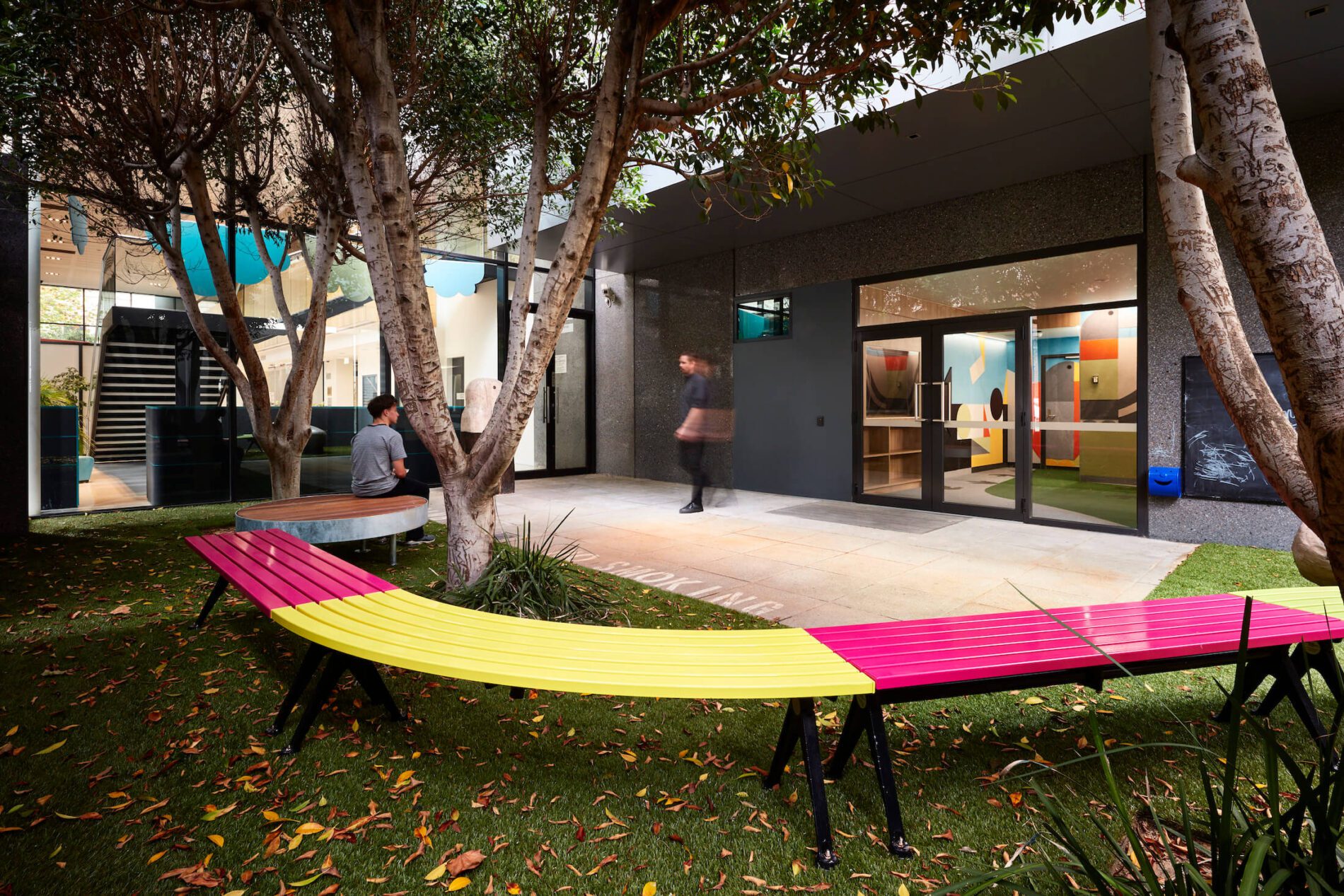 Pink and yellow bench seating in external courtyard overlooking Children's Court internal entry