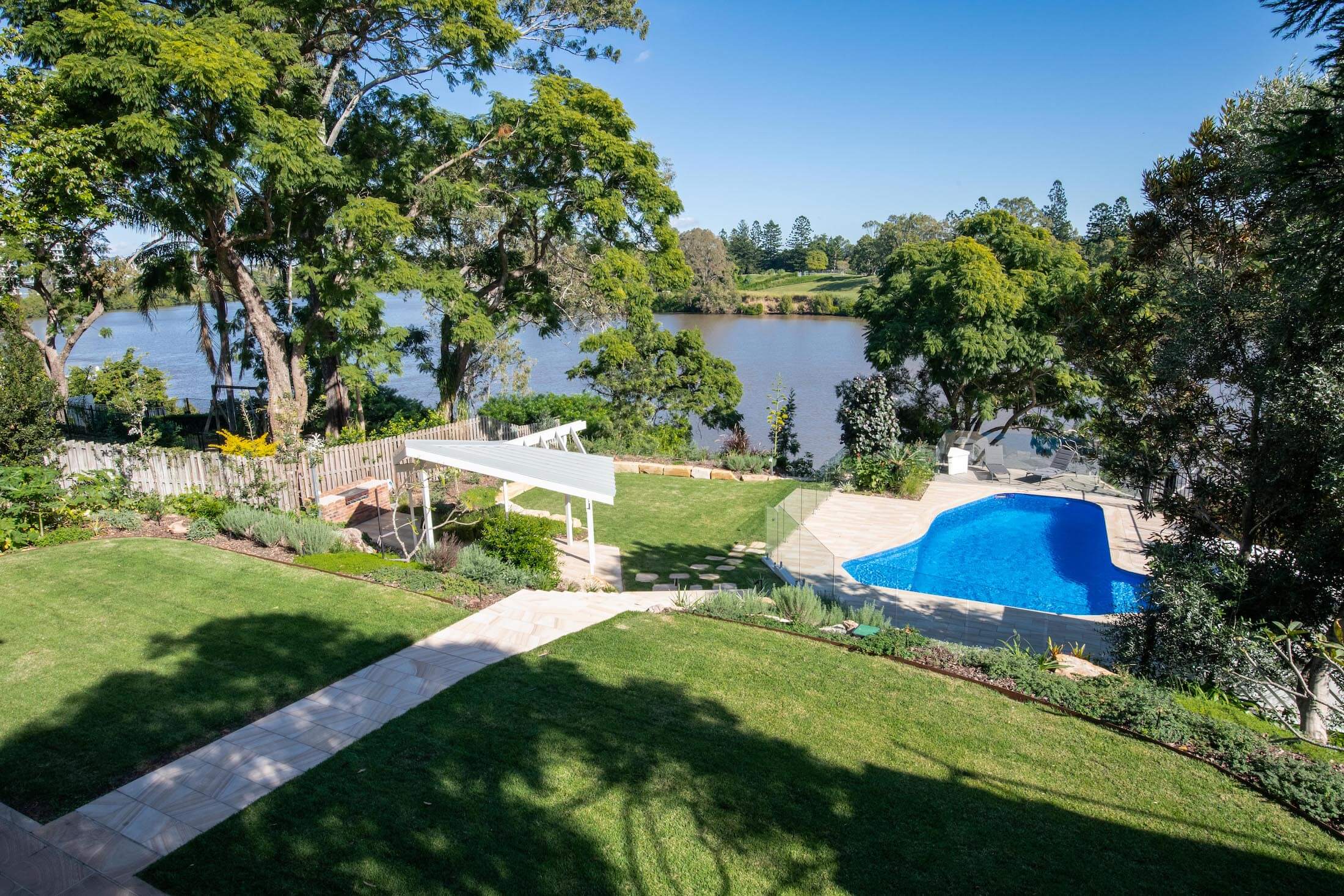 Views across Brisbane River and landscaped yard with pool and pergola