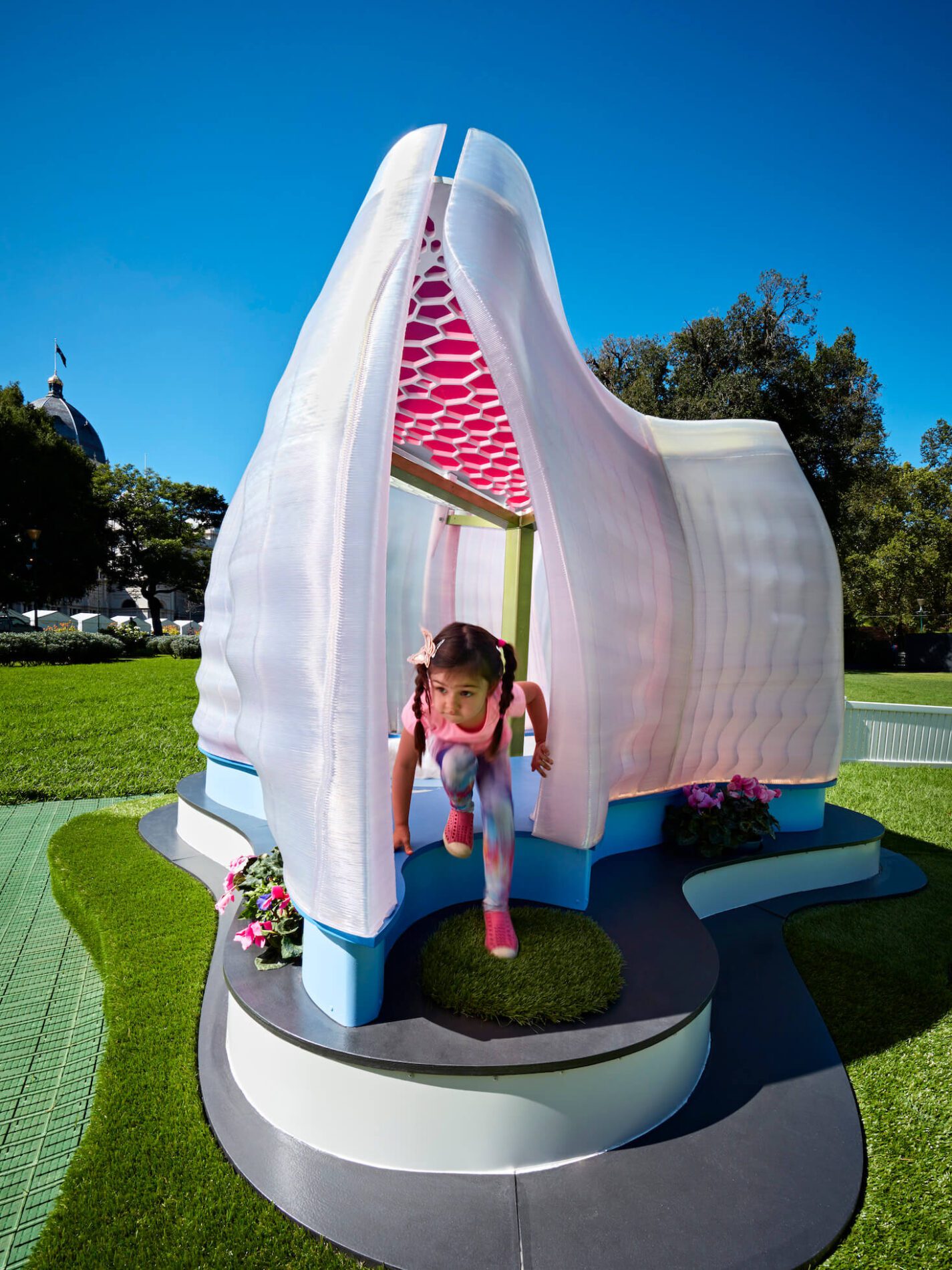 Child emerges from organic pink shaped cubby structure