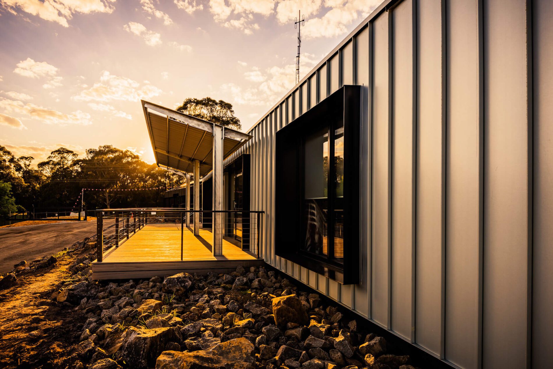 Standing seam metal clad industrial building with slanted canopy over deck at sunset
