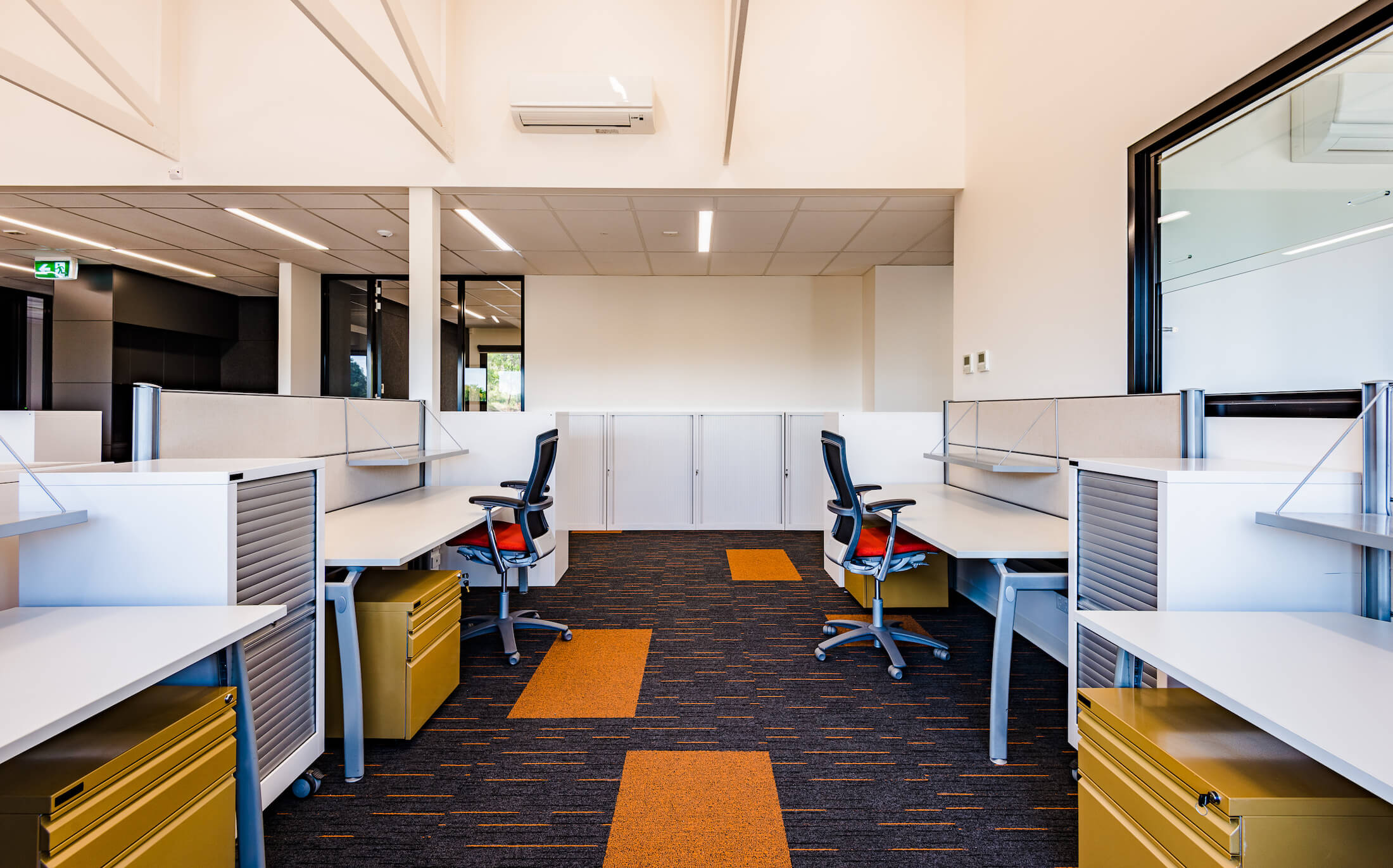 Office with laminate desks, dark grey carpet with orange rectangular and striped pattens