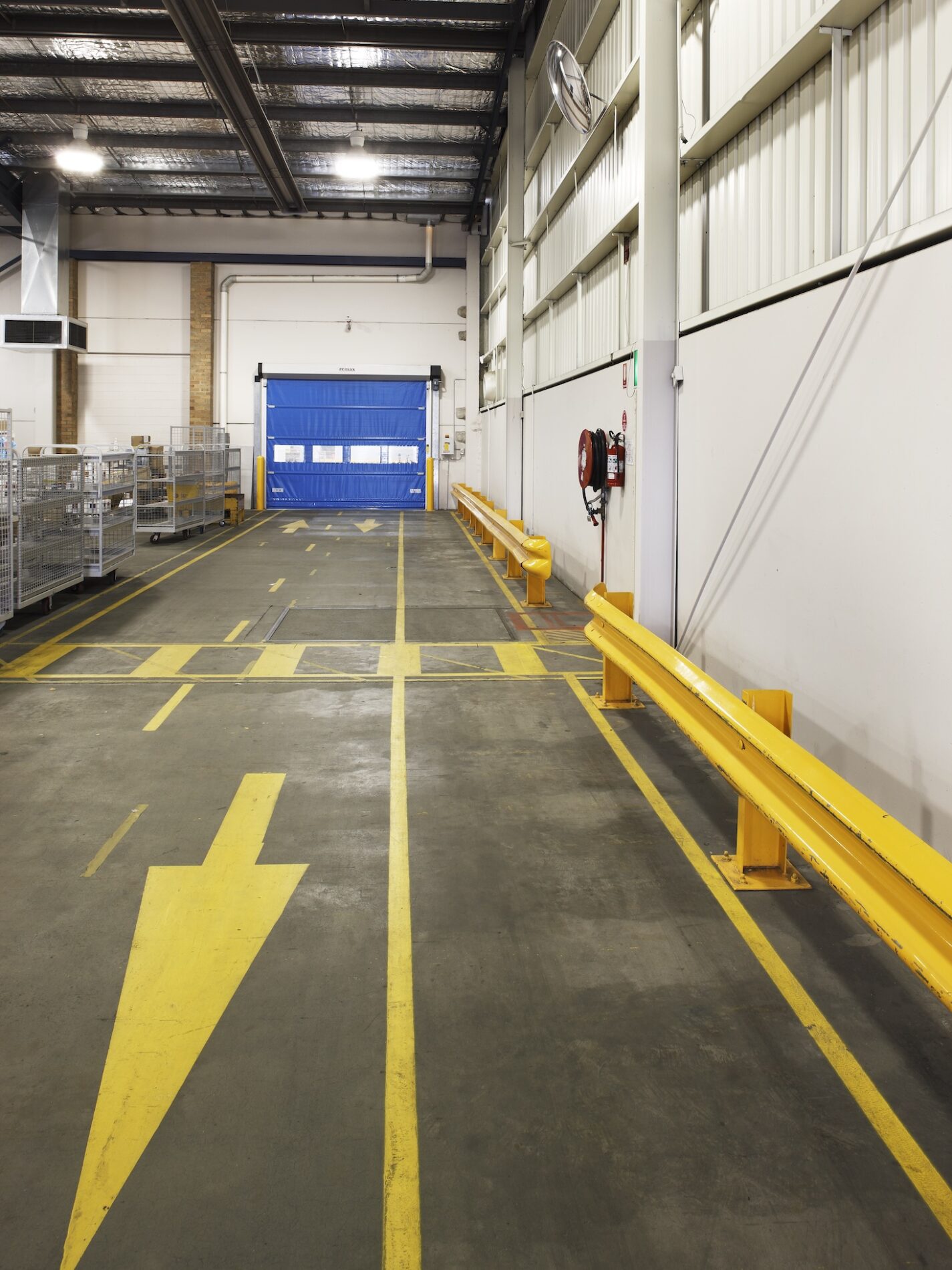 Australia Post warehouse entry and exit way from roller door with yellow barriers and yellow line markings