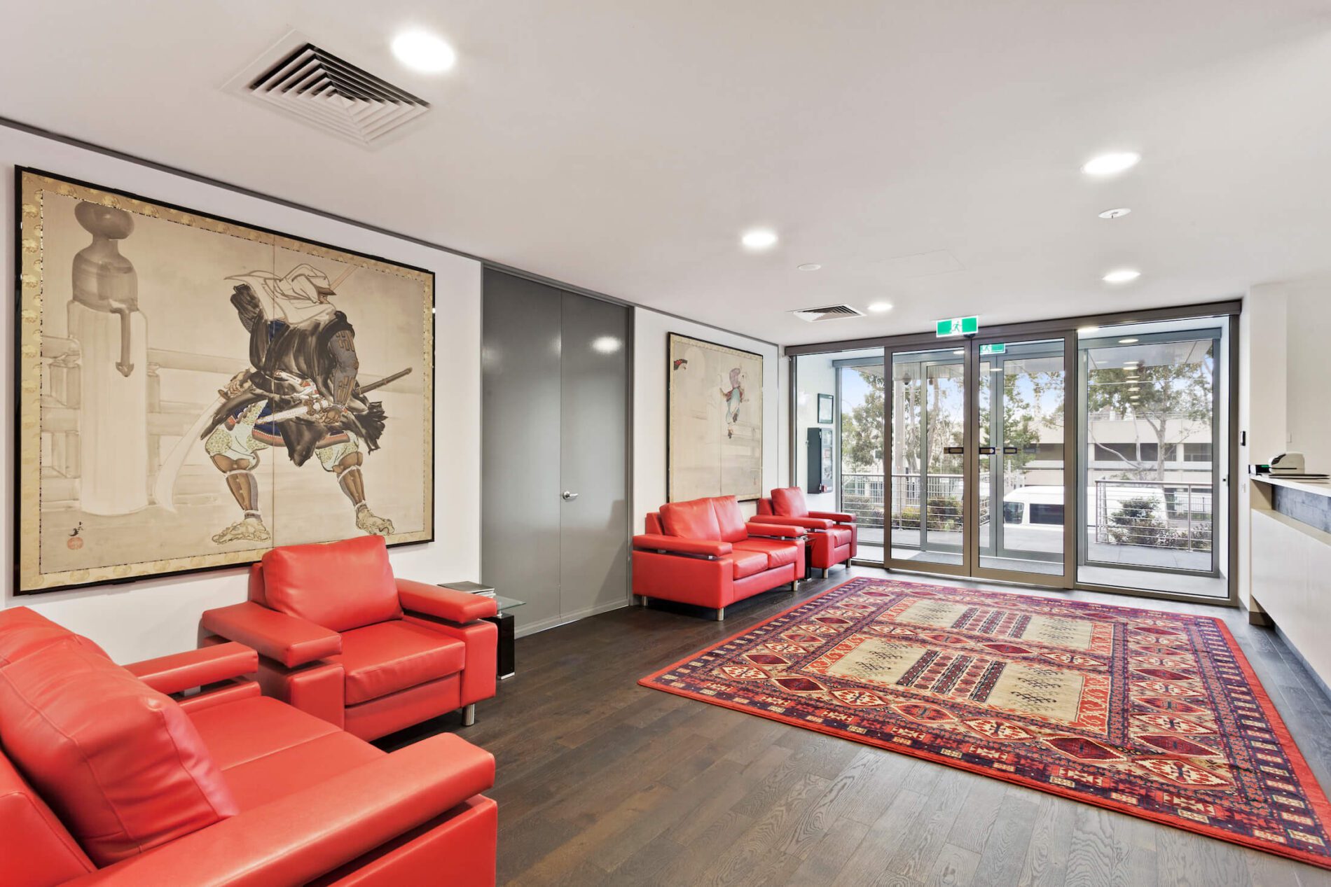 Reception to commercial space with red leather chairs and rug on floor