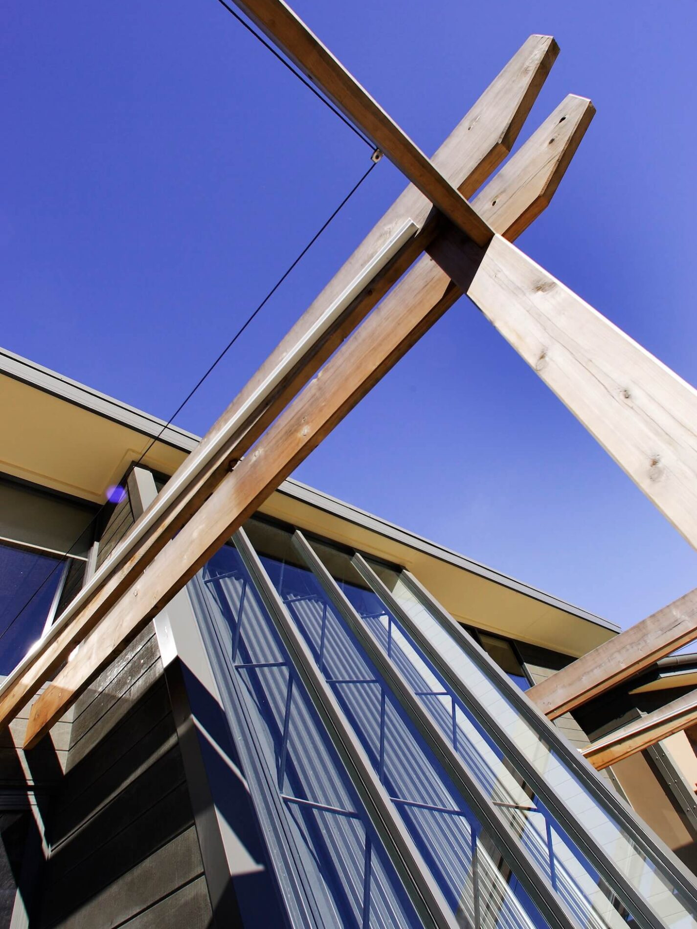 Looking up at timber posts, pully wire attached, facade of building and blue sky behind