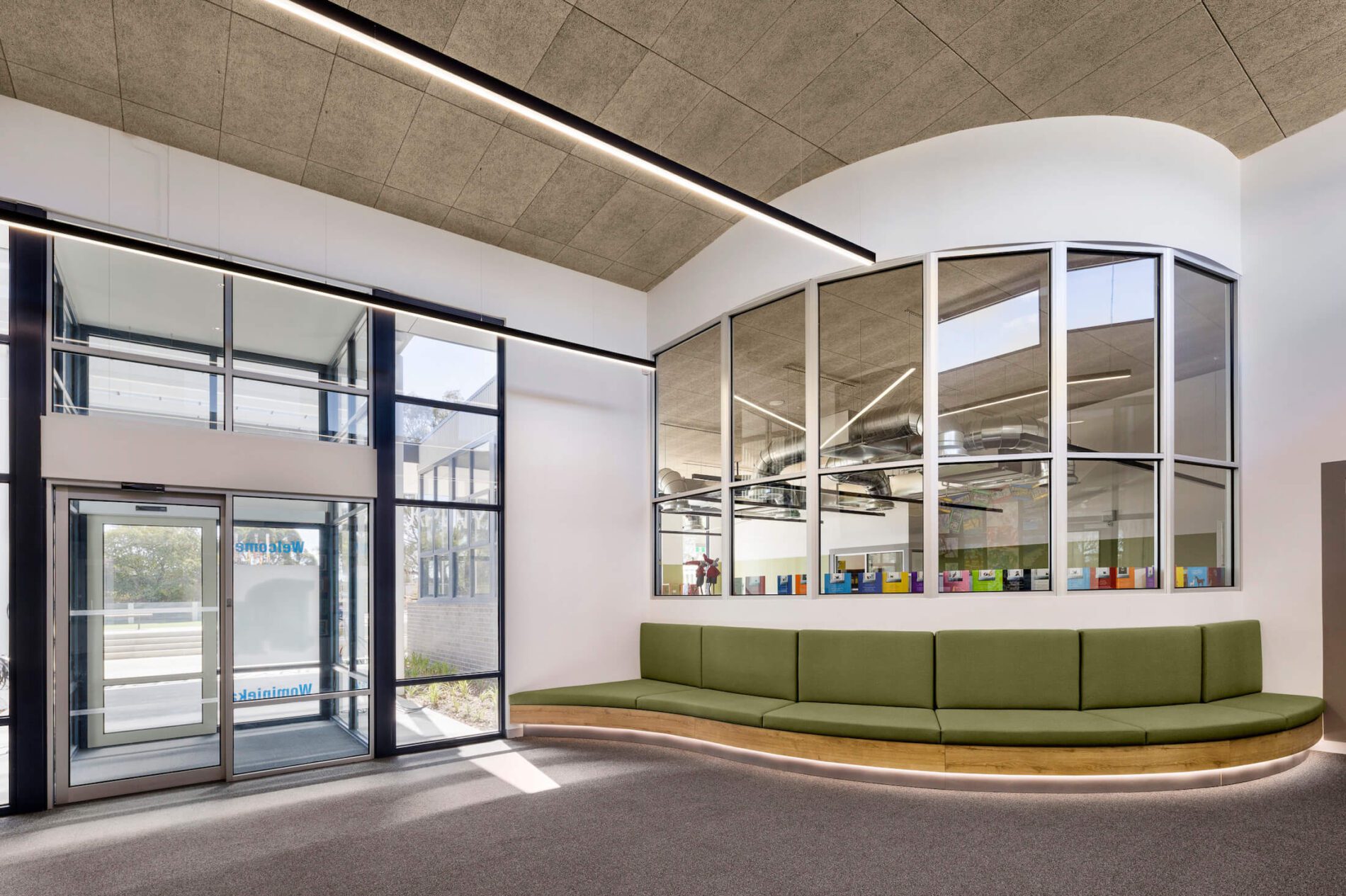 Curved green banquette seating in school administration entry with strip lighting above.