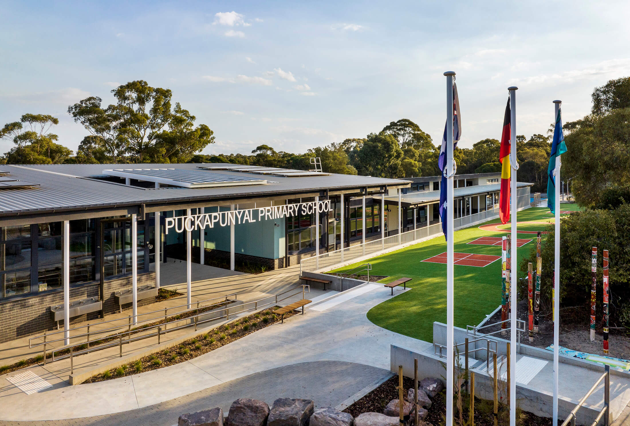 Puckapunyal Primary School forecourt with ram and stairs, turfed areas and flags in foreground.