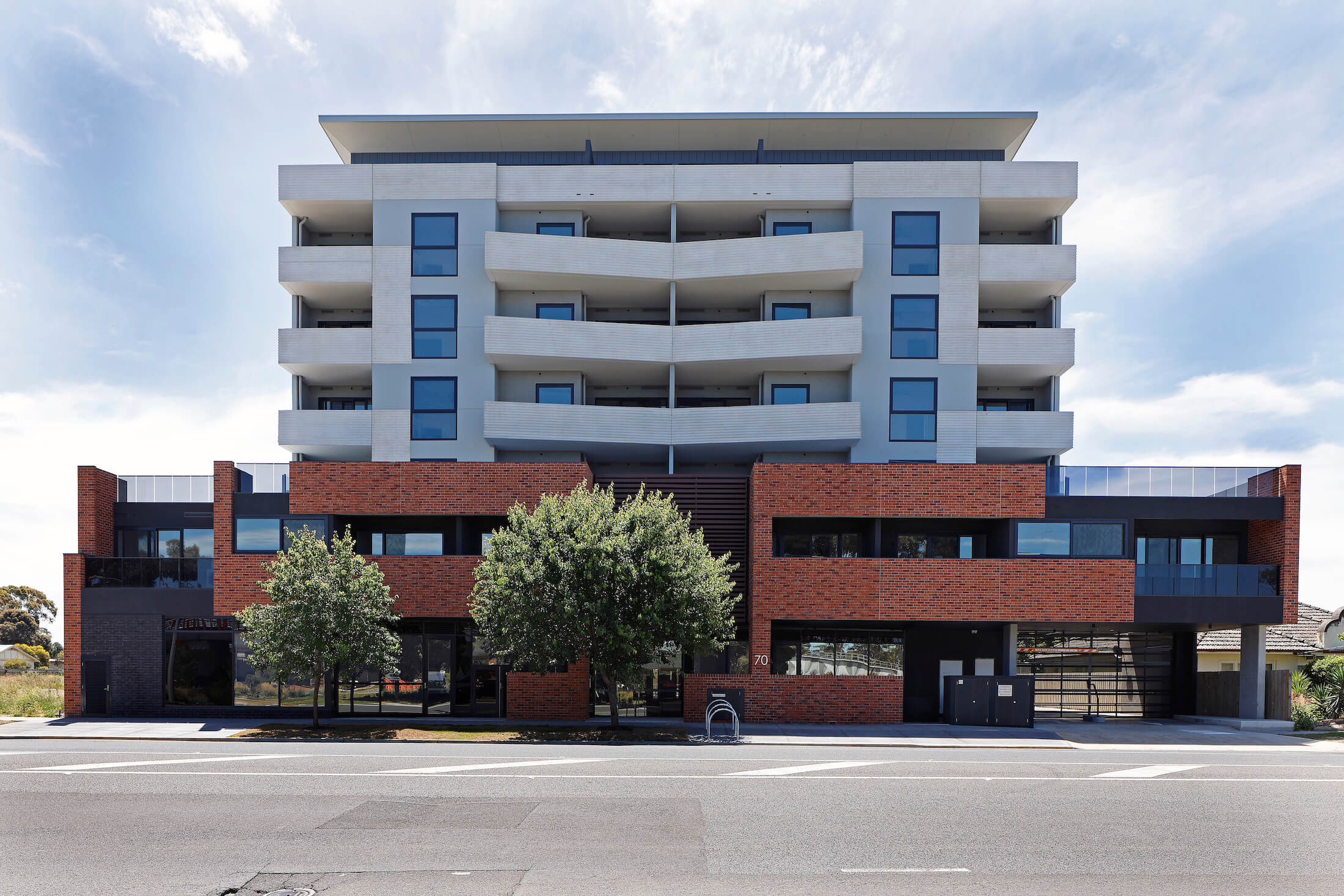Large residential building with brick plinth and recessive lighter coloured upper floors
