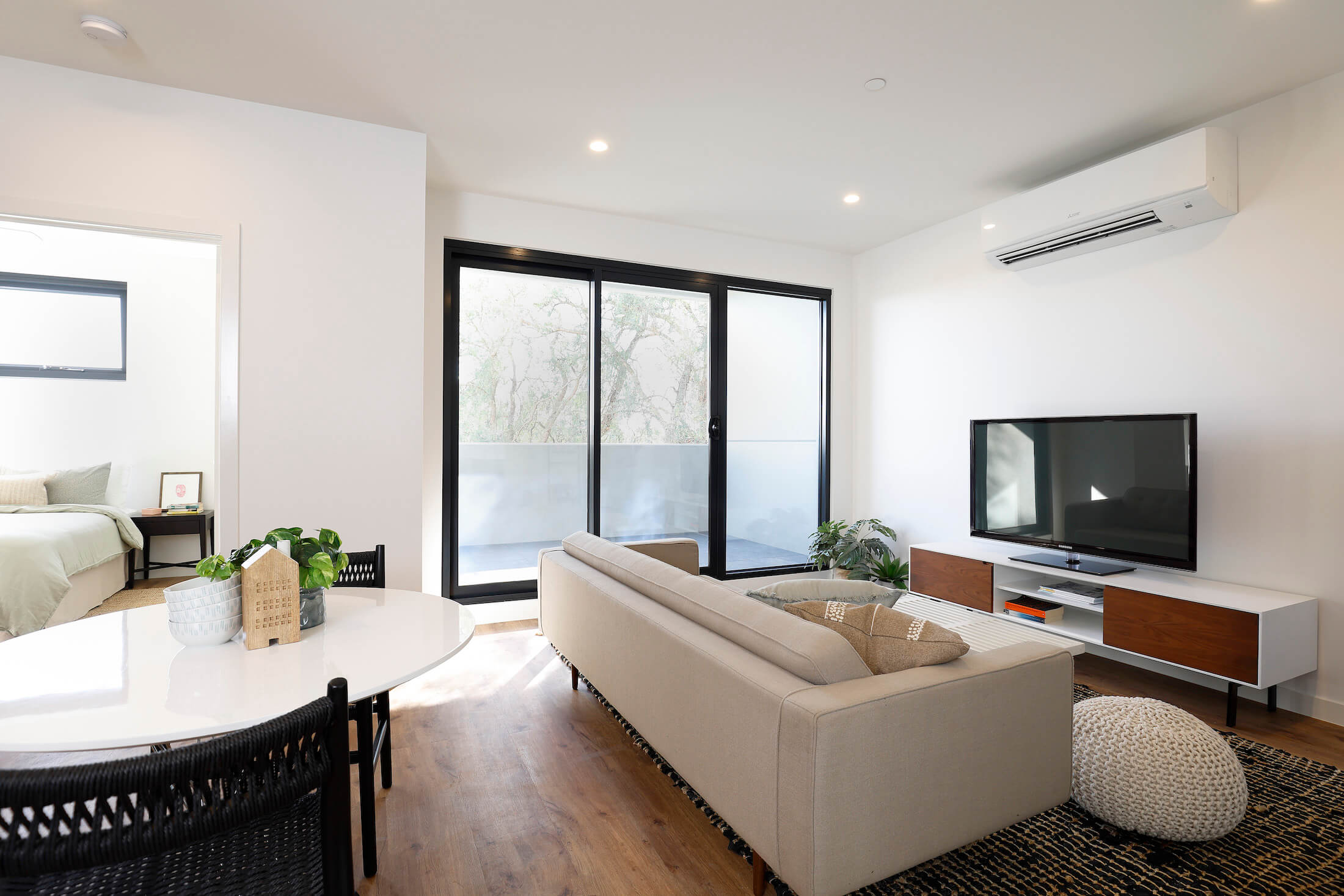 Bright living room space with white walls, timber-look flooring, balcony beyond