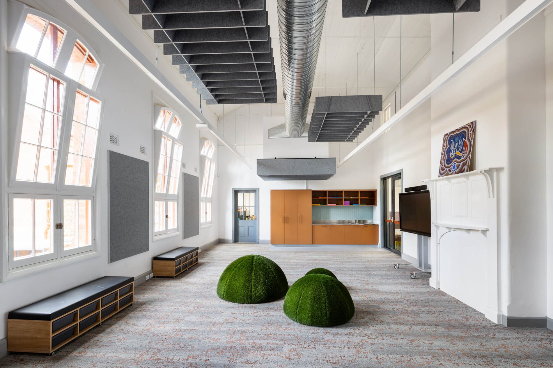 Multipurpose learning space in heritage building with three small grass cushion mounds