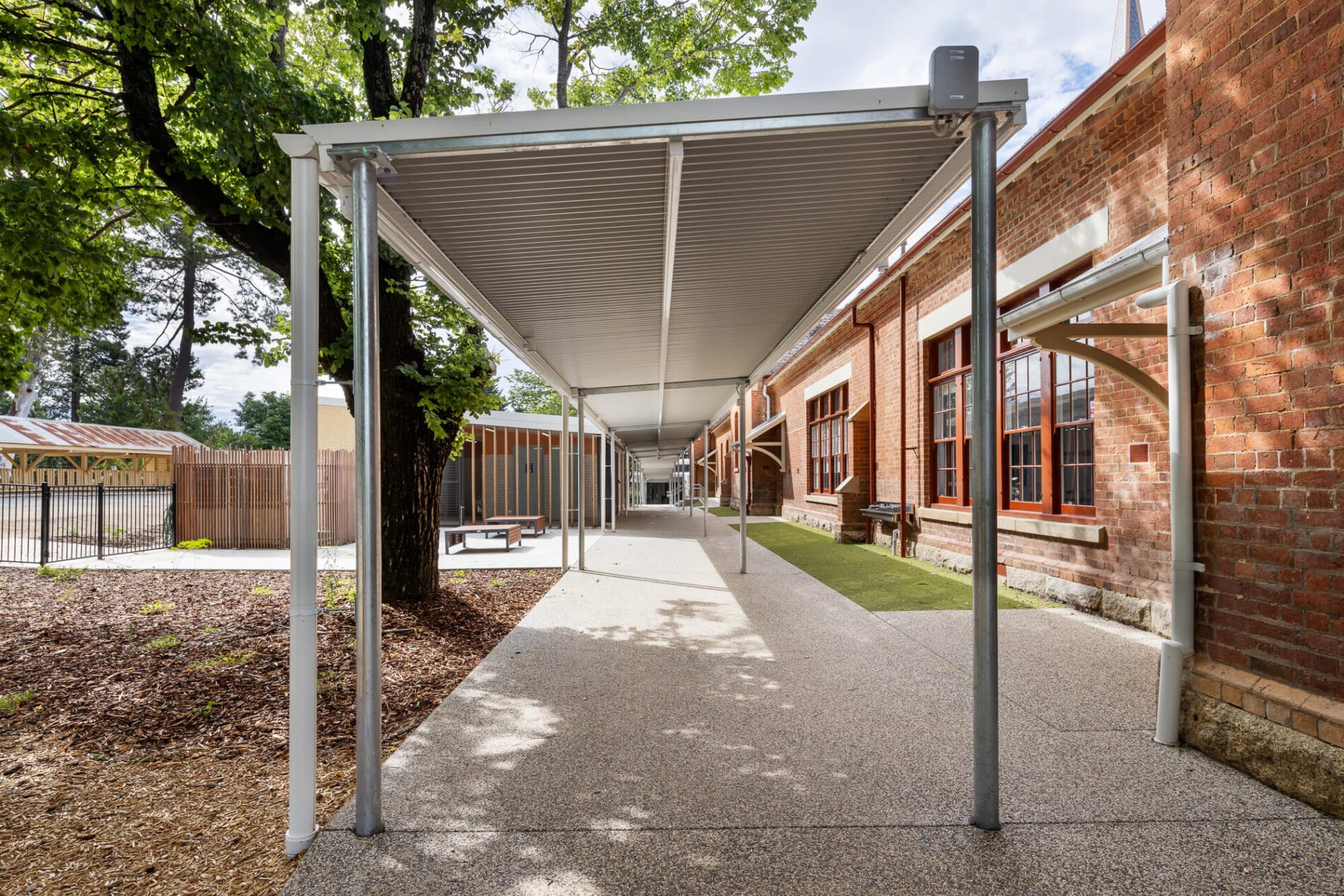 Covered walkway parralel to but separated from heritage school building