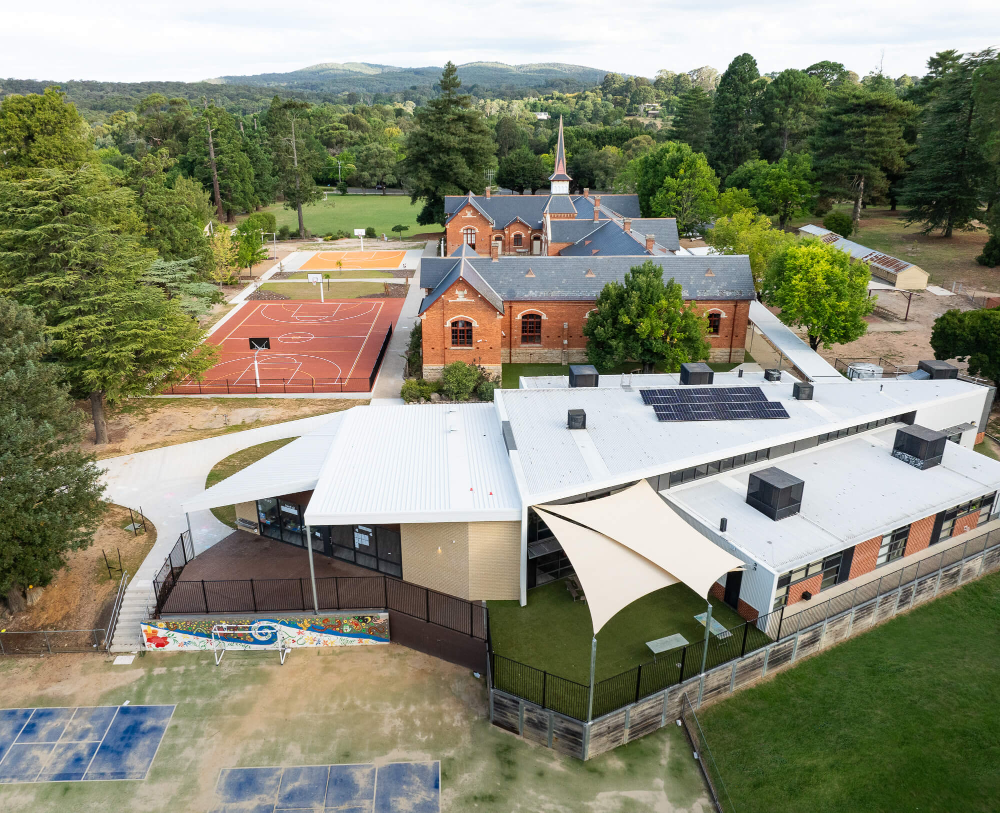 Side aerial view of heritage brick school building with multipurpose BER and new addition