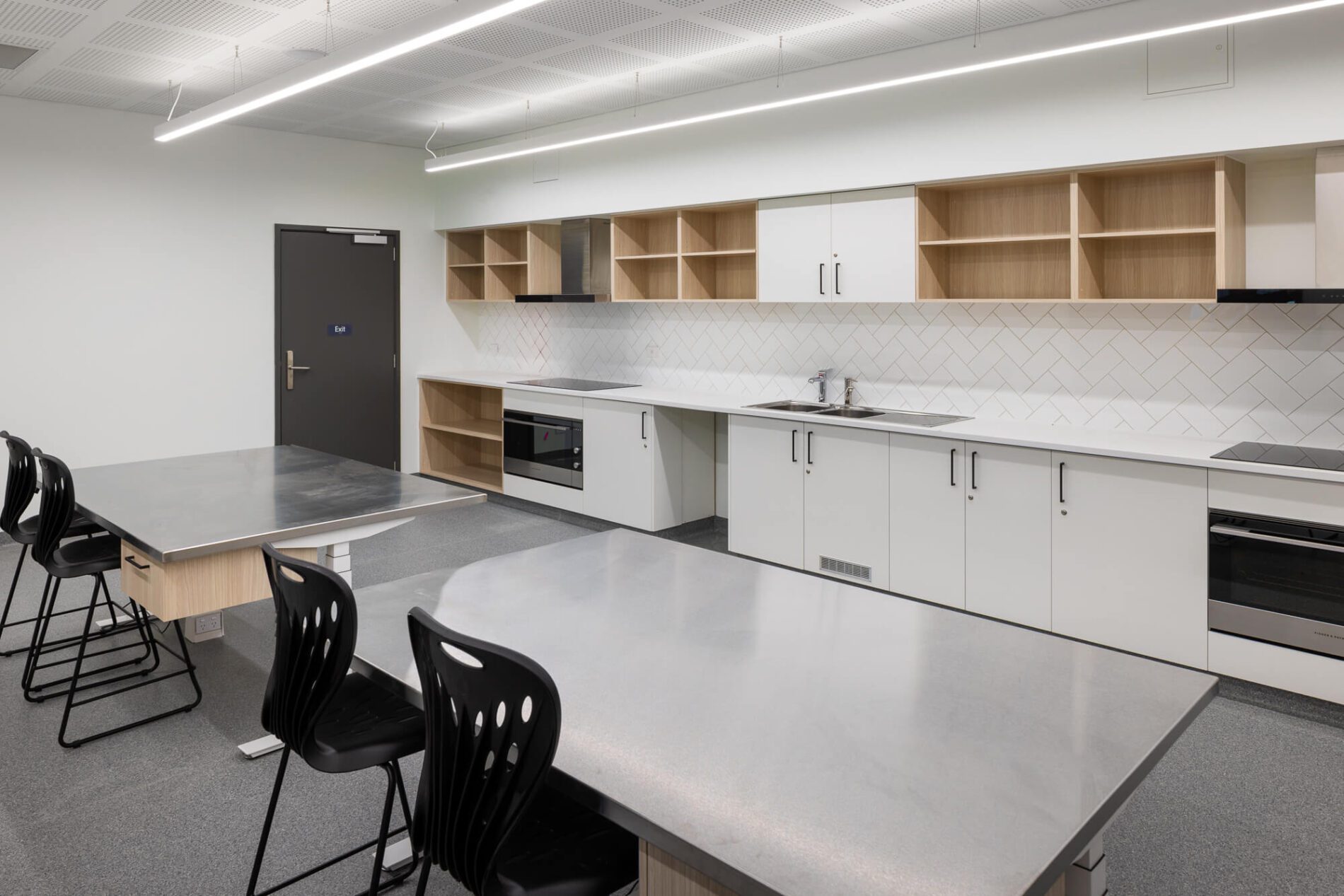 Kitchen space with stainless steel benches, white upboards, timber laminate shelving.
