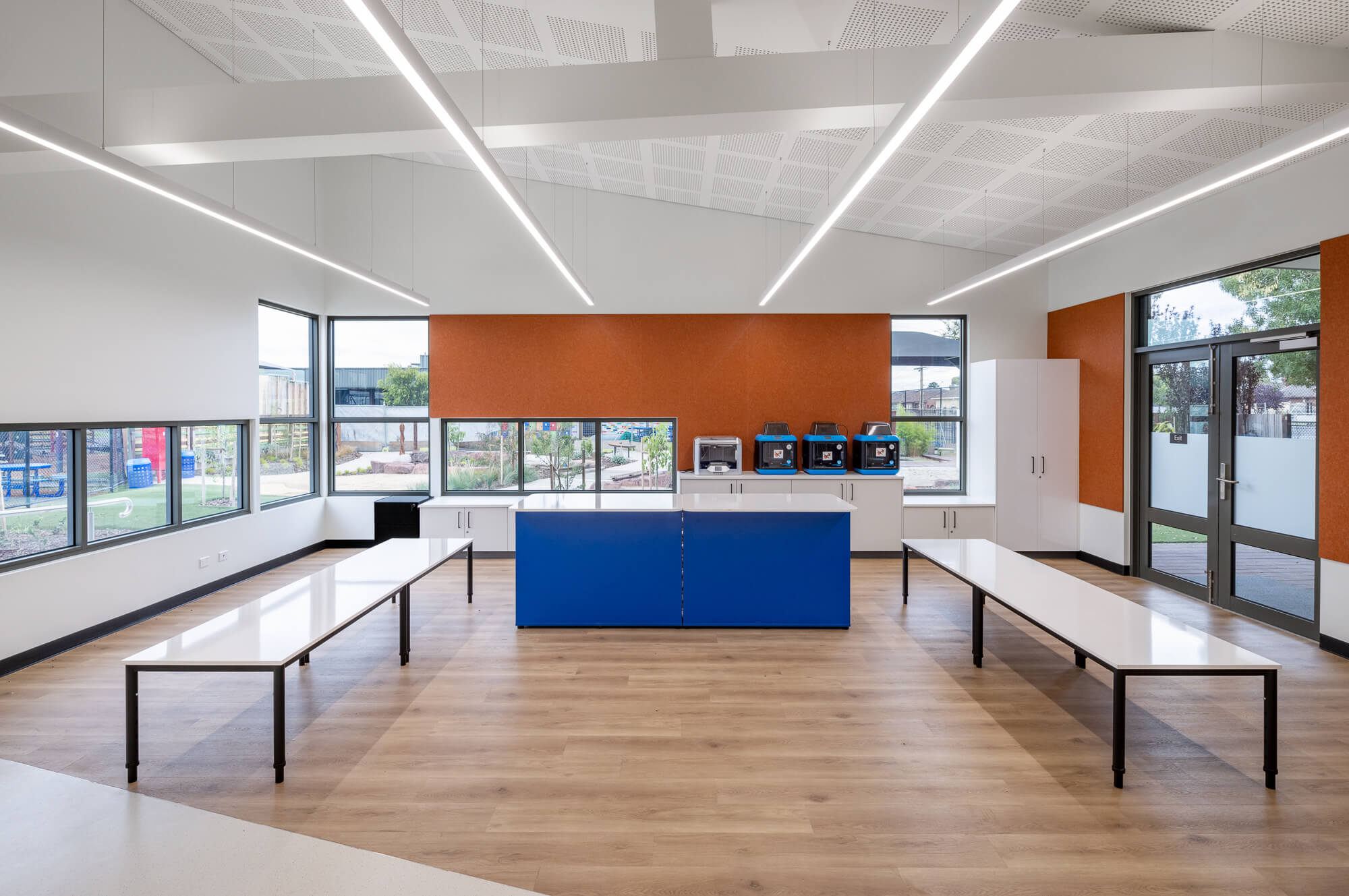 Wet area classroom with windows all around at student height, feature orange wall treatment