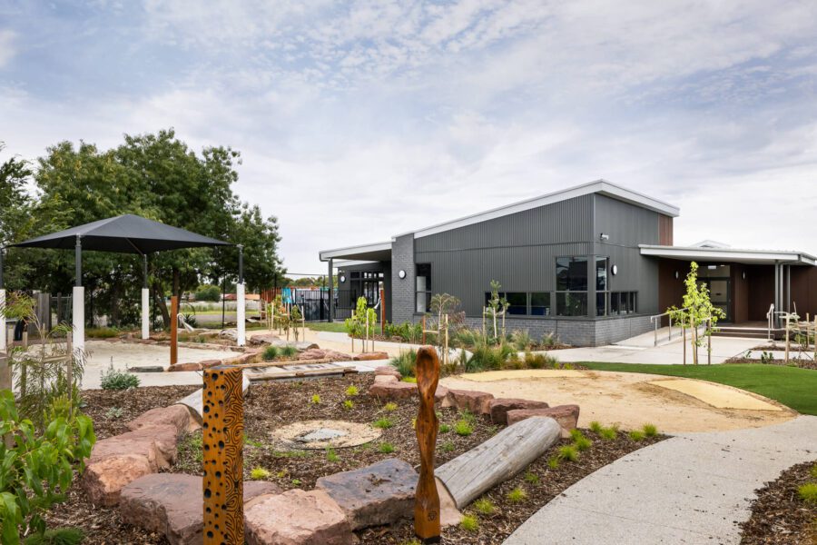 Grey school building with landscaped garden space with yarning circle in foreground